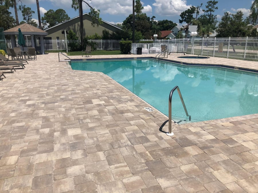 Tan tumbled paver deck around a community pool and spa
