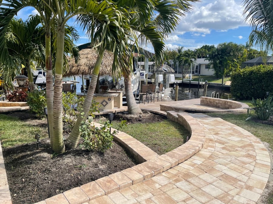 Curved paver walkway leading to a waterfront dock and tiki hut