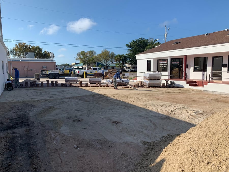 Crew screeding sand for a commercial courtyard paver install