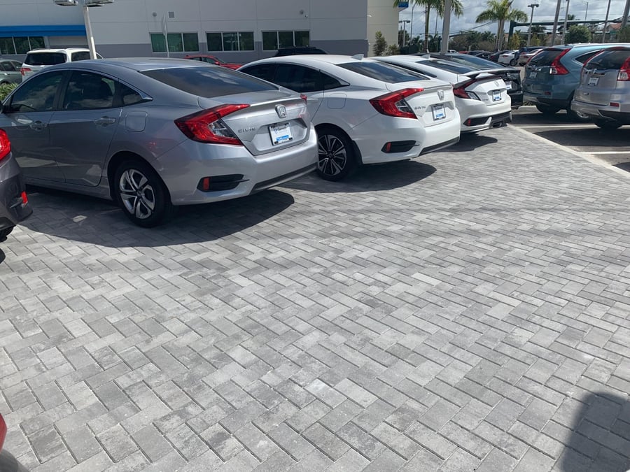 Car dealership display lot in gray herringbone pavers