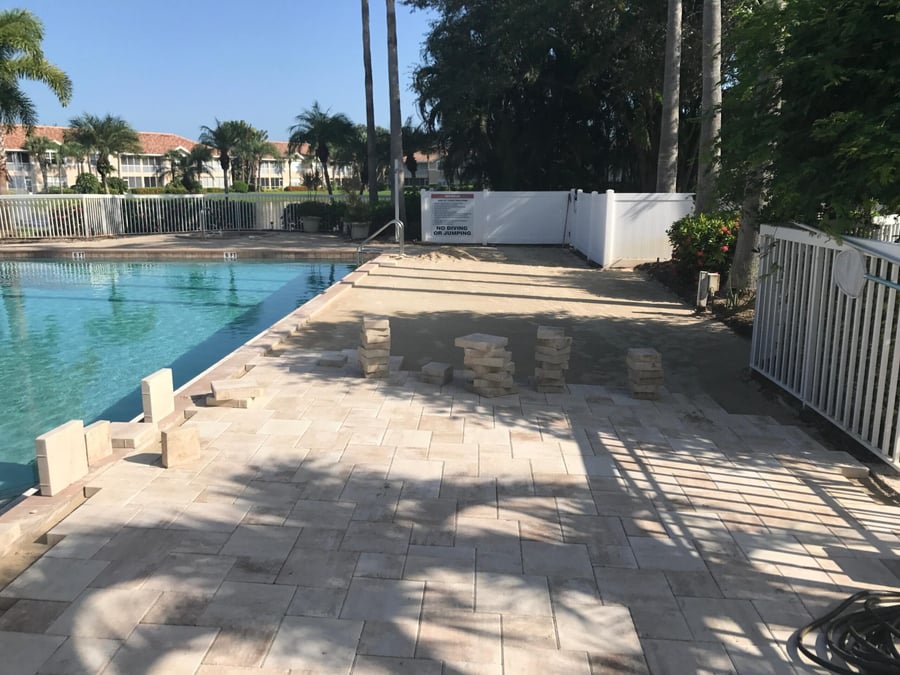 Travertine pool deck installation in progress at a community pool