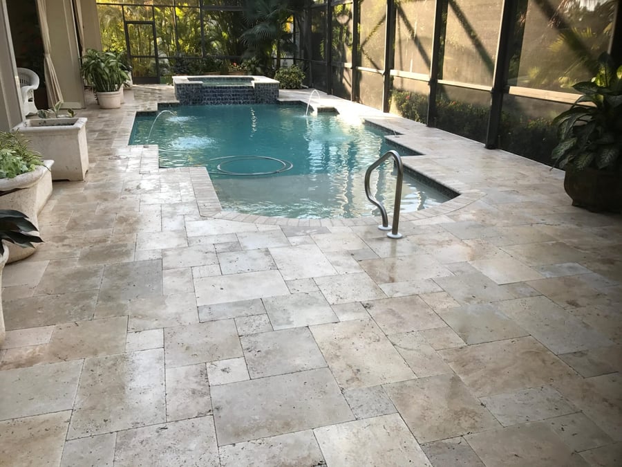 Classic travertine lanai pool deck with brick accent banding