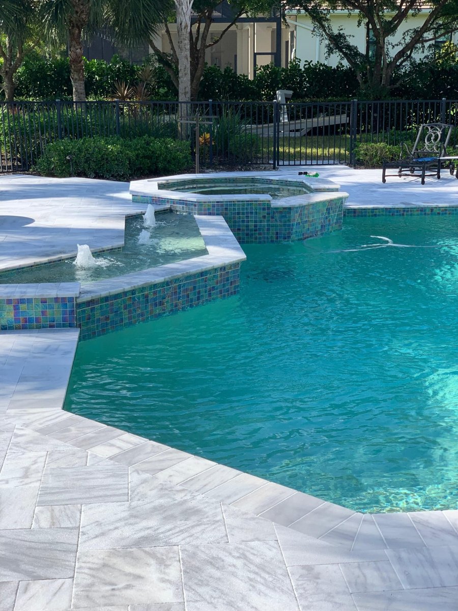 Marble paver pool deck with spillover spa and glass tile
