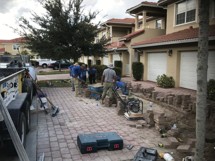 Crew rebuilding paver bands and compacting base on a condo driveway repair