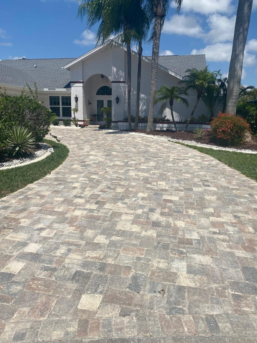 Curved tumbled paver driveway to an arched entry