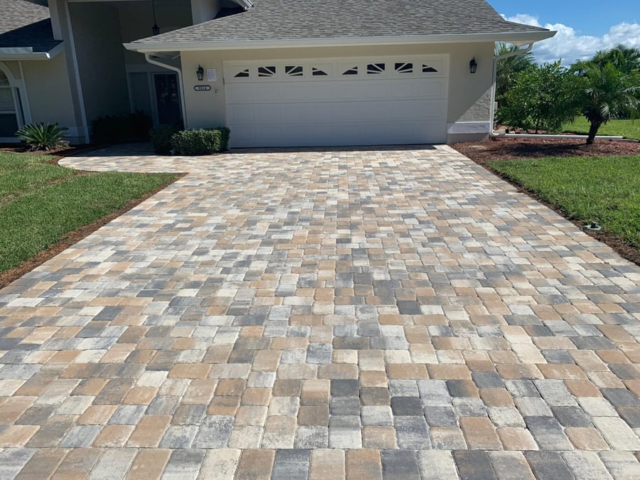 Cobble blend paver driveway leading to a two car garage