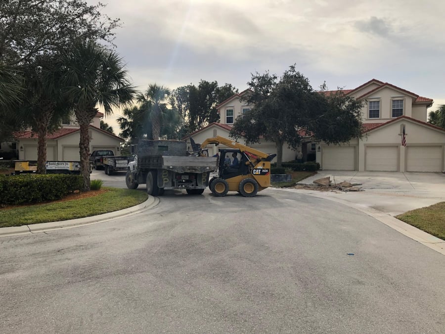 Skid steer and dump truck removing an old concrete drive at carriage homes