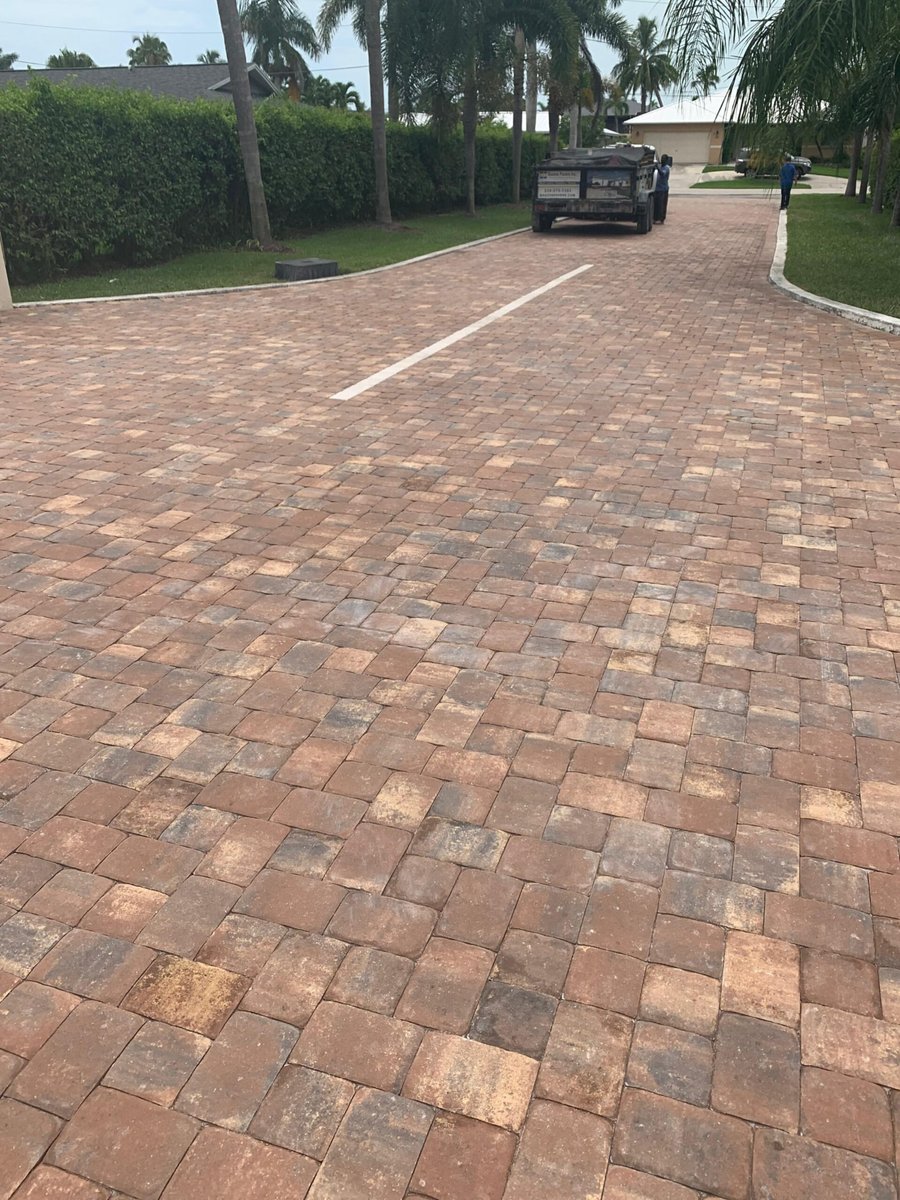 Wide terracotta-toned paver driveway with Bastos dump truck at the garage