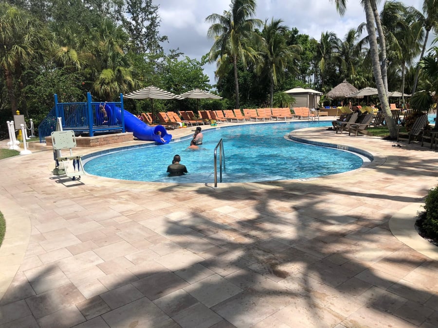 Resort family pool with travertine deck, slide and lounge chairs