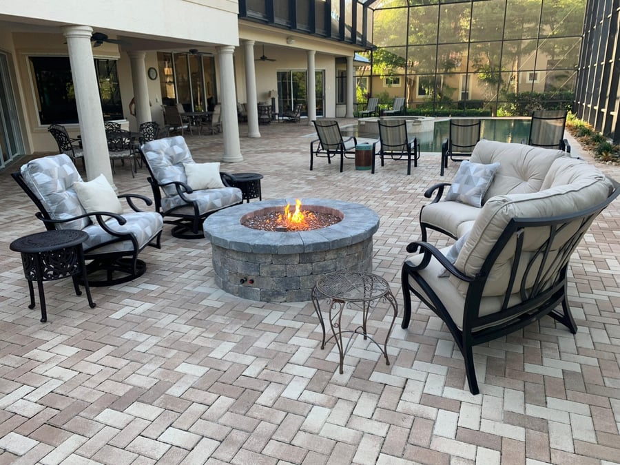 Herringbone paver patio with a round gas fire pit and lounge seating