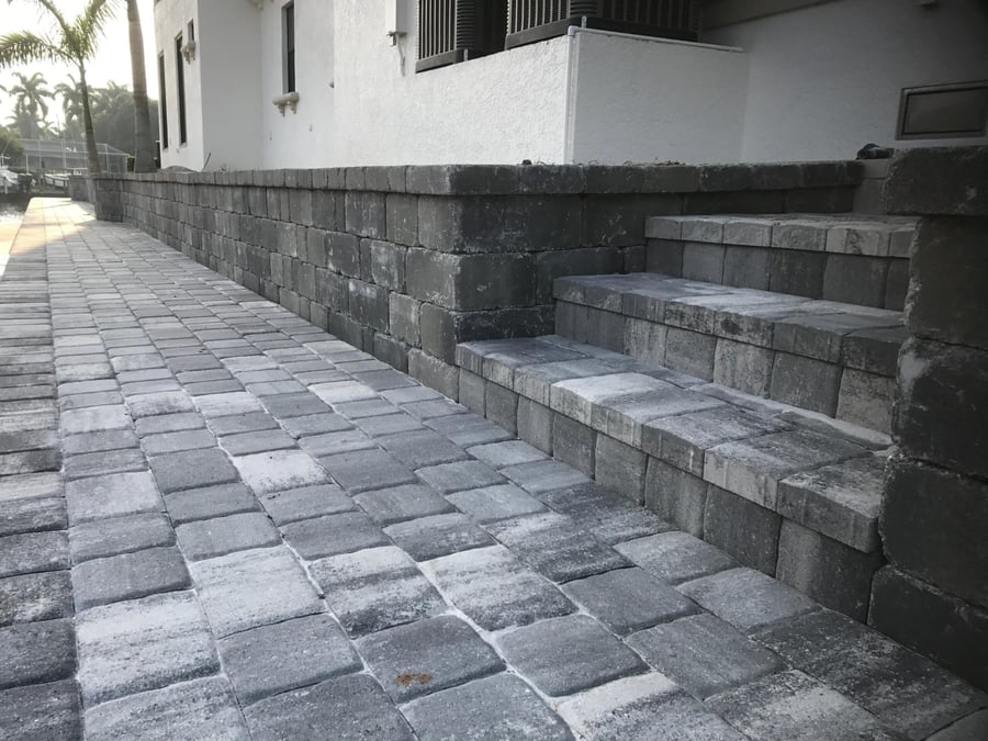 Gray retaining wall with paver steps along a waterfront walkway
