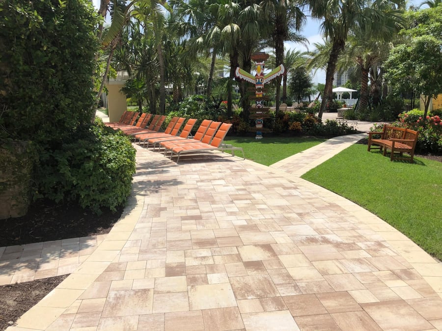 Wide travertine garden walkway beside resort loungers