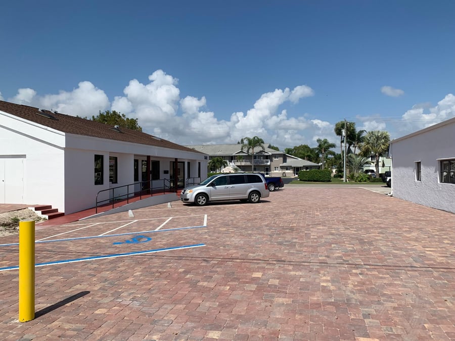 Office building parking lot paved in red brick pavers with striped stalls