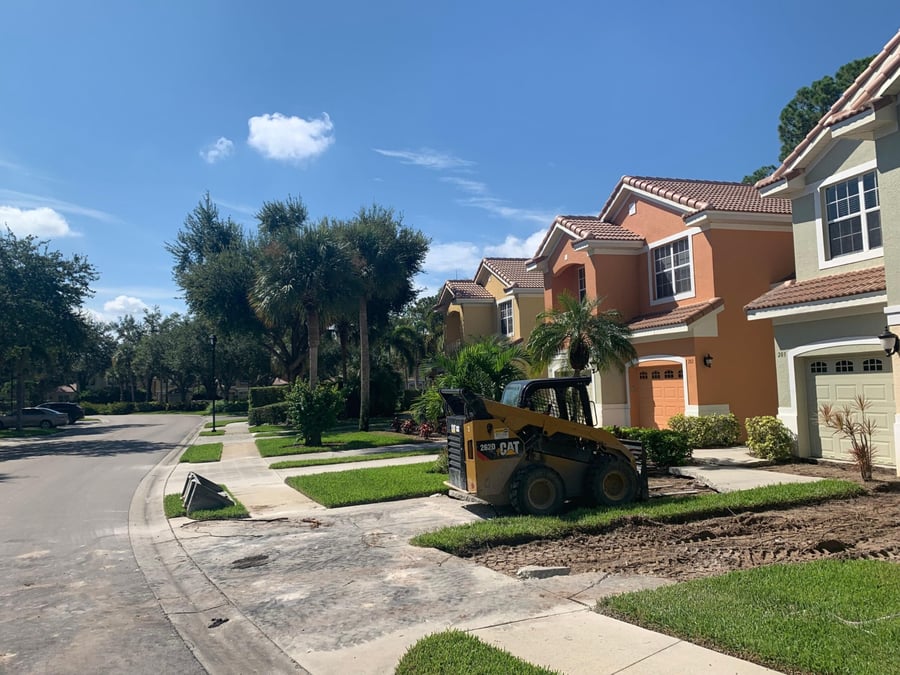Skid steer removing a townhome driveway in a residential community