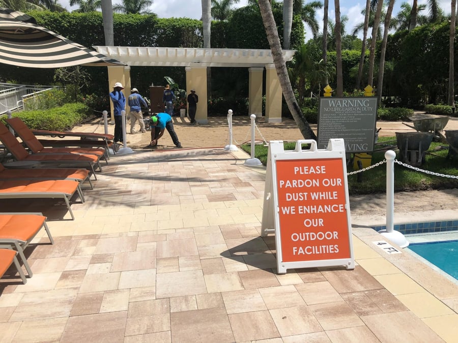 Crew installing travertine pool deck pavers at a resort