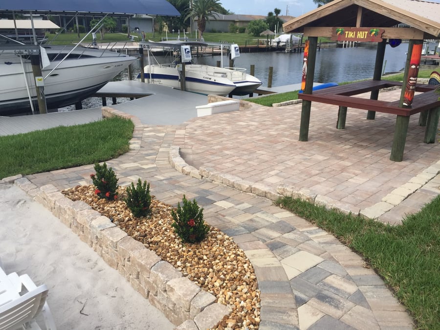 Paver walkway and patio with tiki hut beside a canal dock