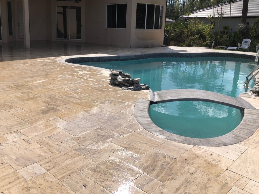 Silver travertine pool deck wrapping a freeform pool and spa
