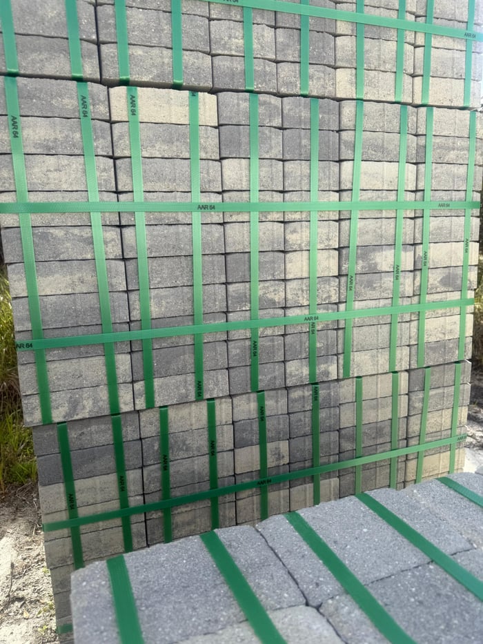 Strapped pallets of gray-blend concrete pavers ready for delivery