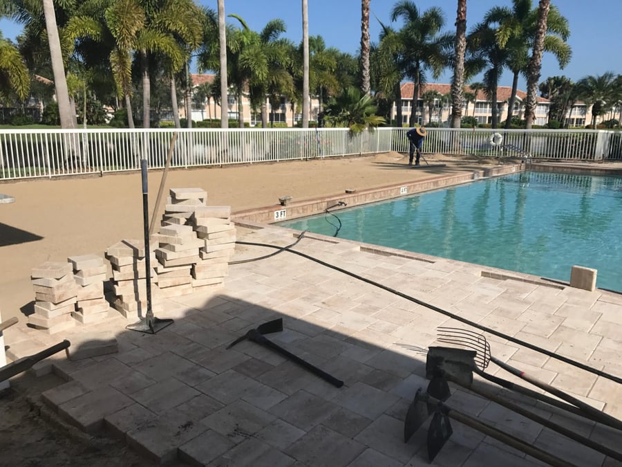 Travertine pool deck installation underway at a community pool