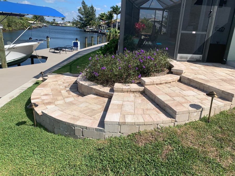 Raised paver walkway and steps wrapping curved planter walls at a waterfront lanai