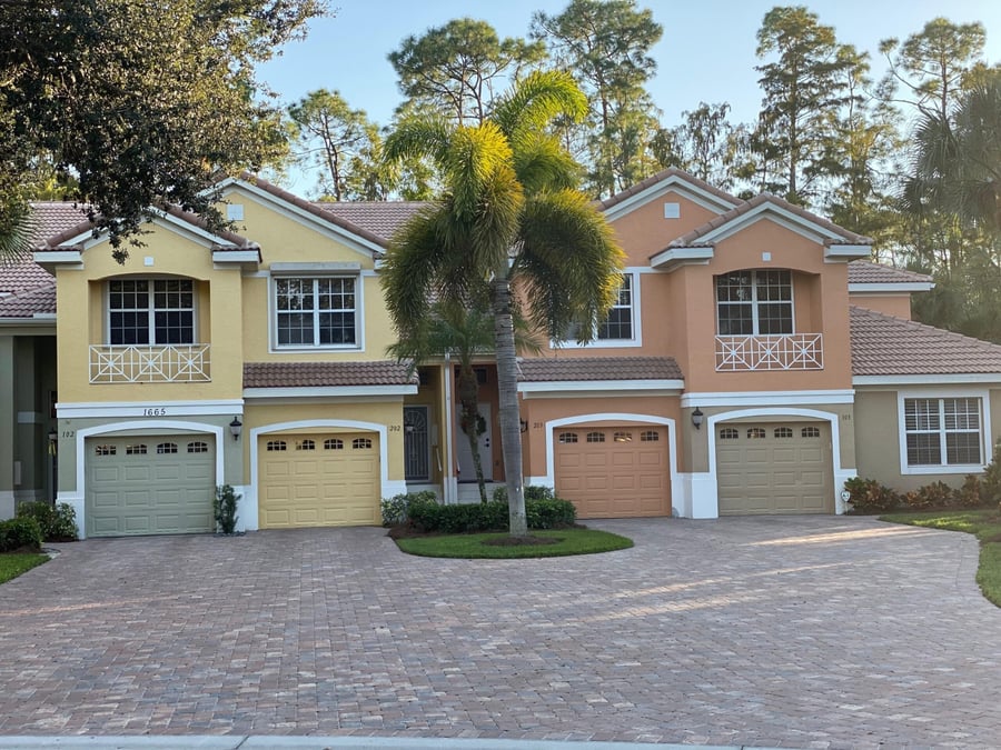 Shared coach home driveway in tumbled pavers with a palm island