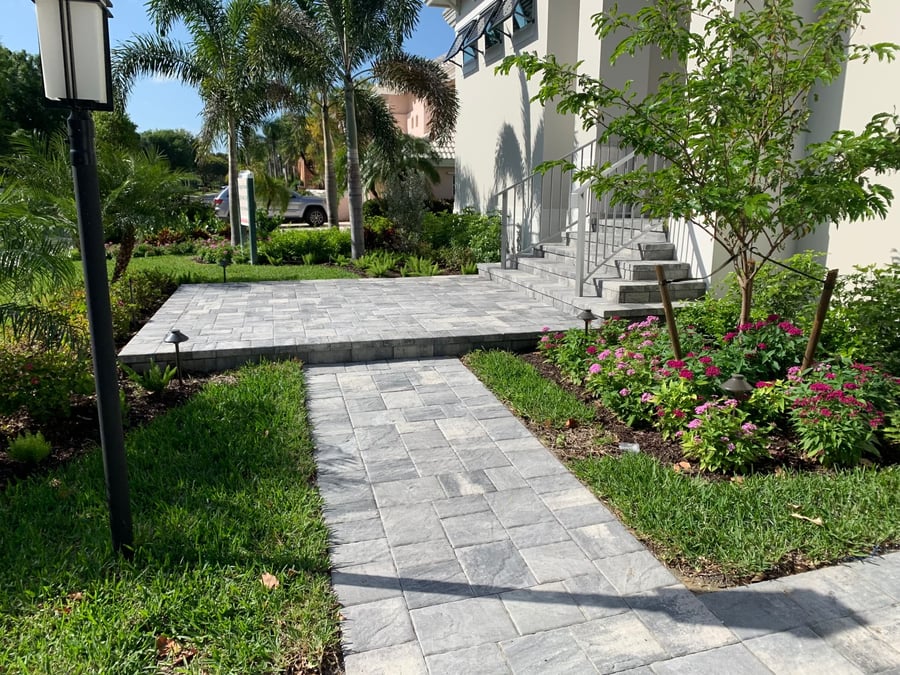 Paver walkway leading to raised entry with steps and columned porch