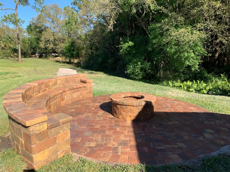 Brick fire pit patio with curved bench overlooking a preserve